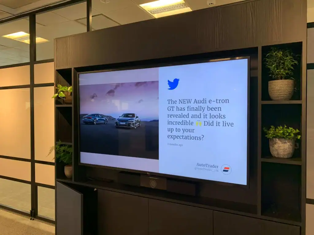 Tabletop plants surrounding a wall monitor at Autotrader, Manchester
