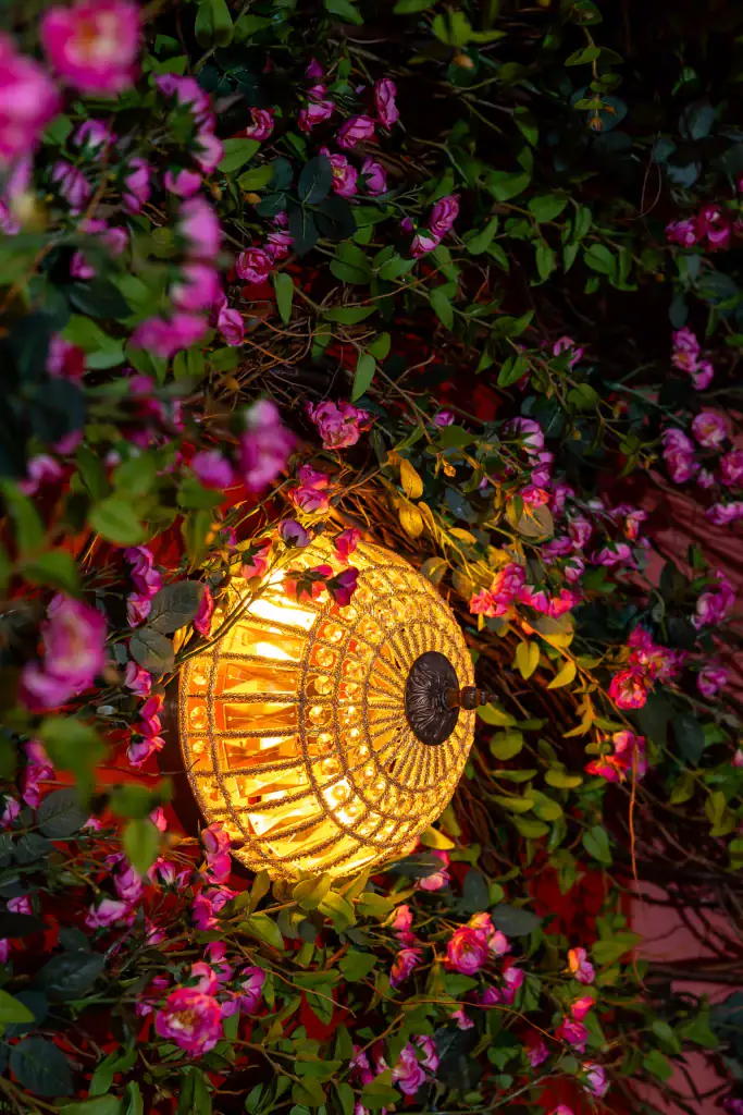 Duchess and Dressmaker wall light surrounded by artificial foliage and pink aster flowers by I Want Plants